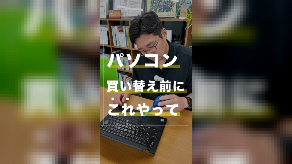 オフィスでノートパソコンの前に座り、青い手動ブロワーを持ってキーボードの掃除をしようとしている眼鏡をかけた男性の姿。画面中央には黄色のマーカー線とともに『パソコン買い替え前にこれやって』という文字が書かれています。