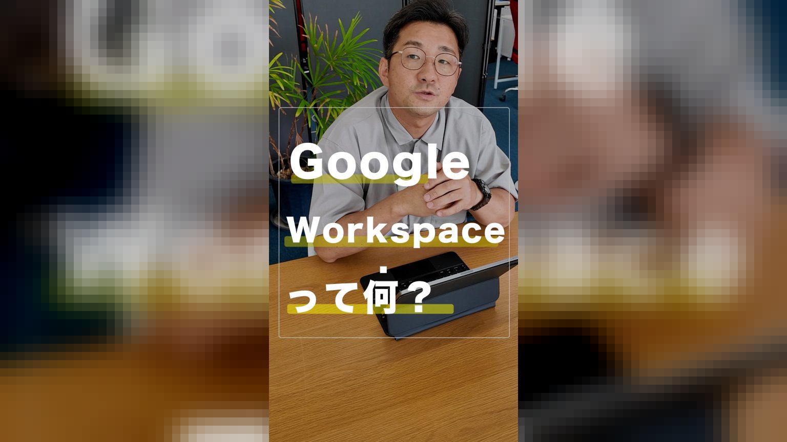 木製のテーブルに置かれたタブレット端末の前に座り、手を組んで話している眼鏡をかけた男性の様子。画面には「Google Workspaceって何？」という白い文字が重ねて表示されている。